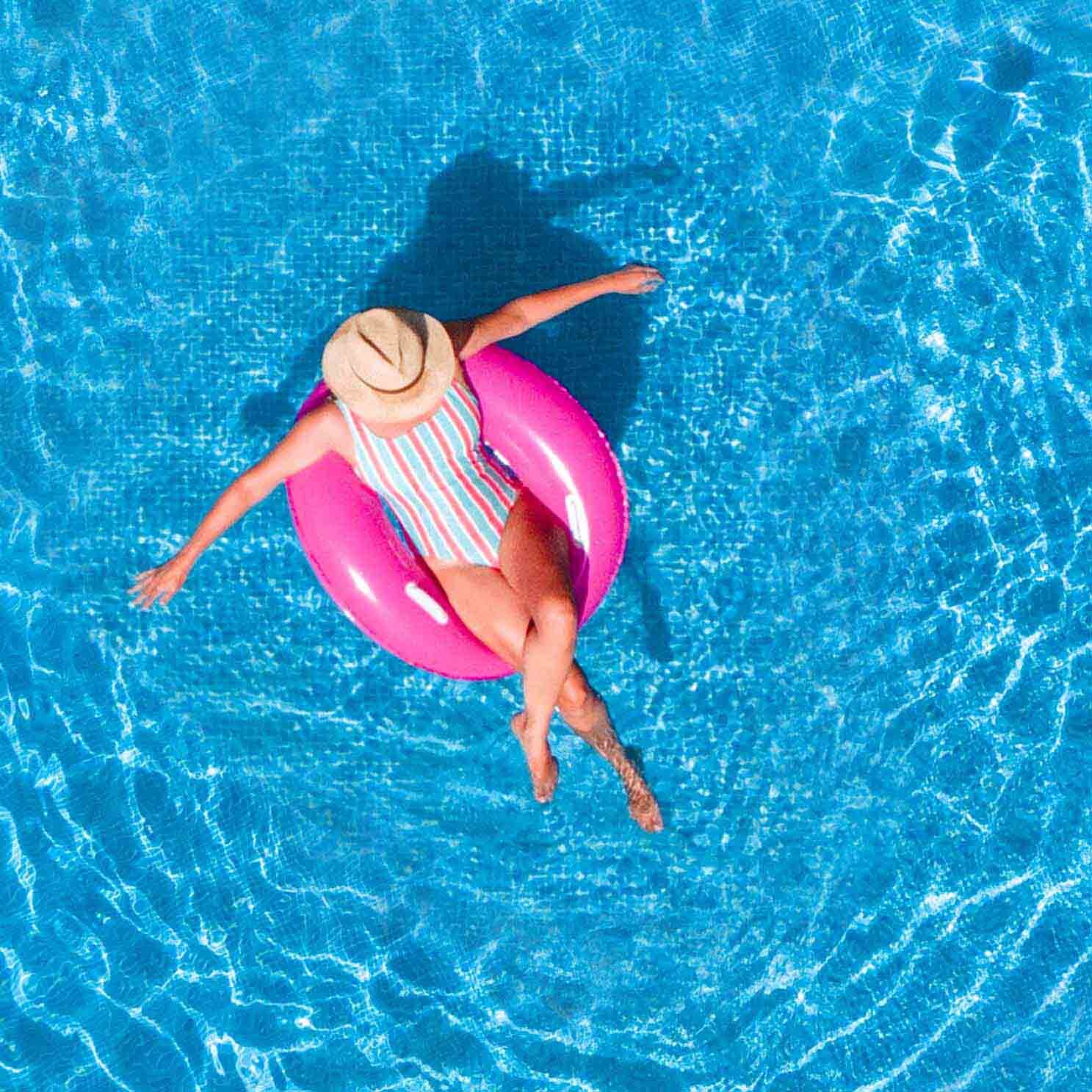 Zenith aerial view of a swimming pool in summer. Young girl in a